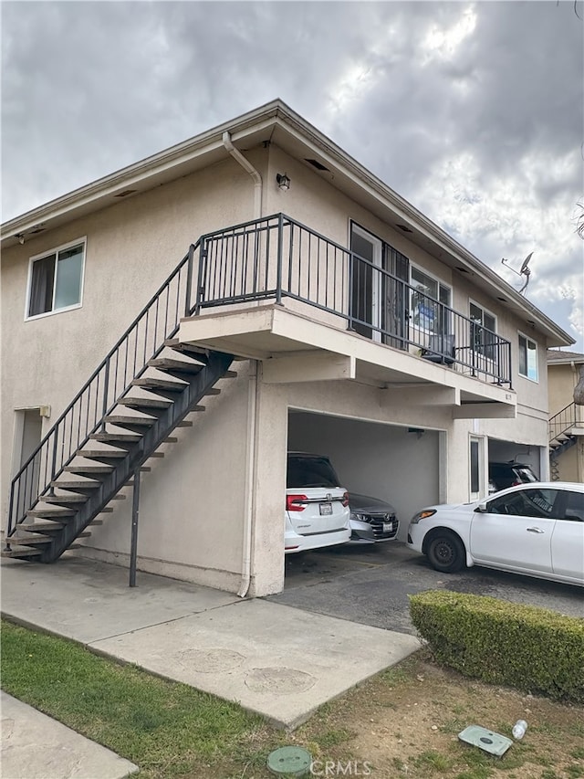 18209 Camino Bello Unit 4, Rowland Heights, CA 91748 - view of property exterior featuring stucco siding, stairway, driveway, and a garage