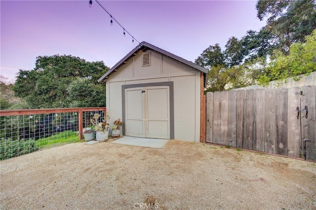 outdoor structure at dusk with a storage shed, an outdoor structure, and fence