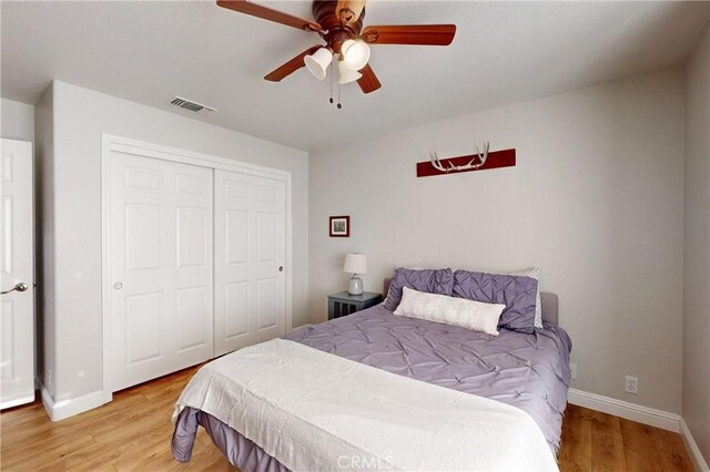 bedroom featuring a closet, wood finished floors, visible vents, and baseboards