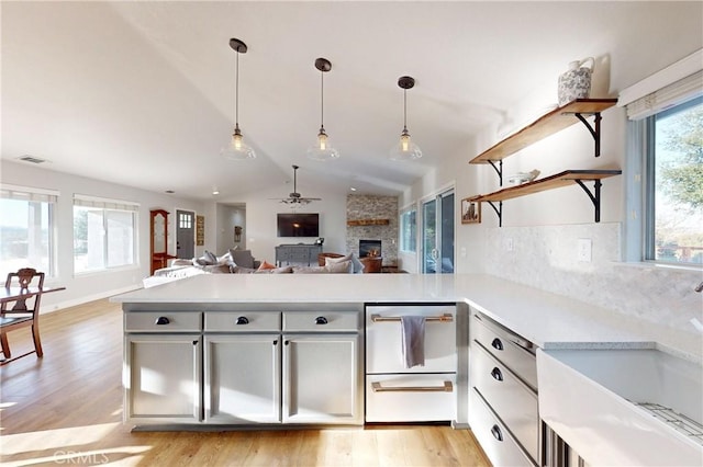 kitchen with a peninsula, open shelves, a sink, and light countertops