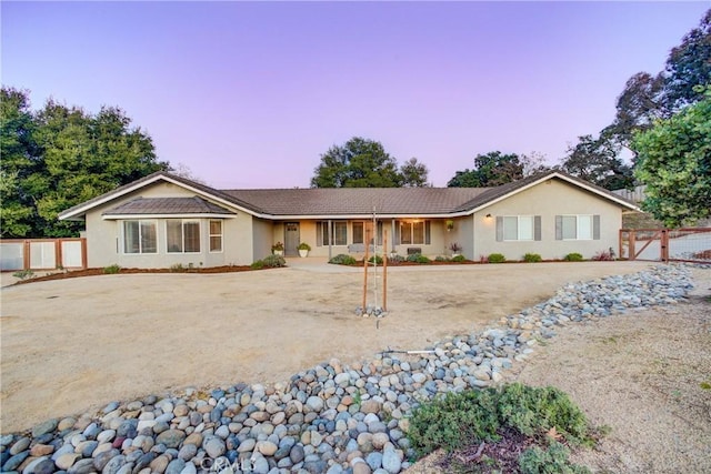 ranch-style house with a gate, fence, and stucco siding