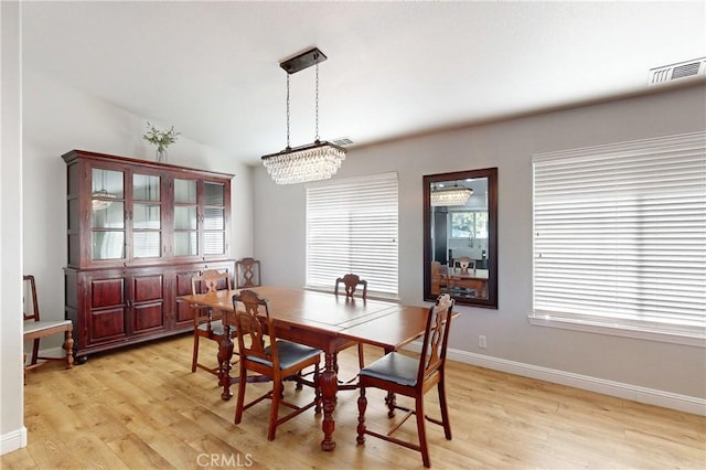 dining room featuring light wood-style floors, baseboards, visible vents, and a chandelier