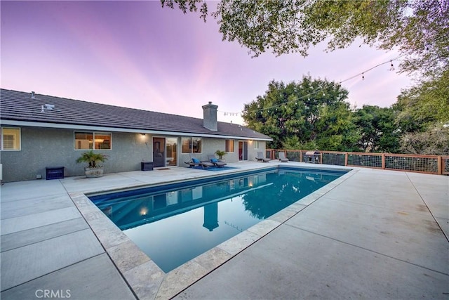 pool at dusk featuring a fenced in pool, a patio area, and fence