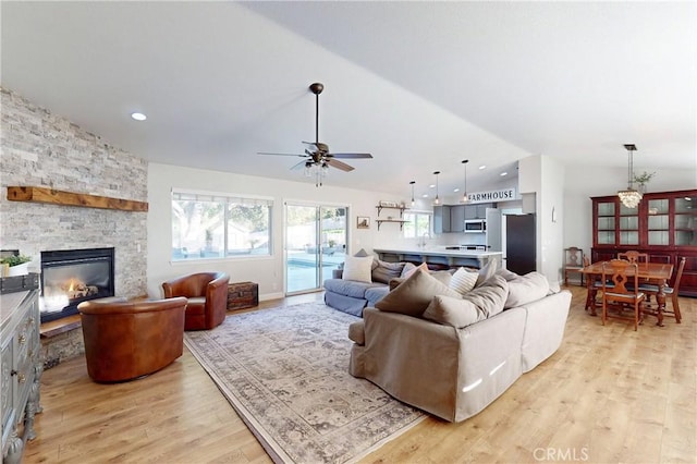 living area featuring light wood finished floors, lofted ceiling, ceiling fan, a fireplace, and recessed lighting