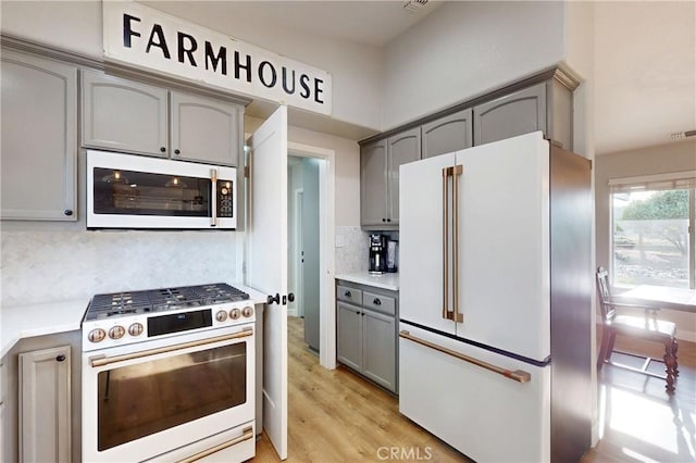 kitchen with white appliances, light countertops, backsplash, gray cabinets, and light wood finished floors