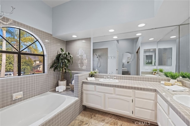 bathroom featuring marble finish floor, a sink, a tile shower, double vanity, and tiled tub