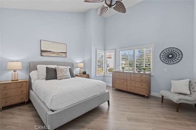 bedroom with baseboards, light wood-style floors, and a towering ceiling