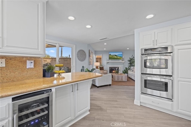 kitchen featuring visible vents, wine cooler, double oven, decorative backsplash, and white cabinets