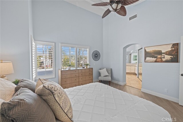 bedroom with visible vents, arched walkways, baseboards, and wood finished floors