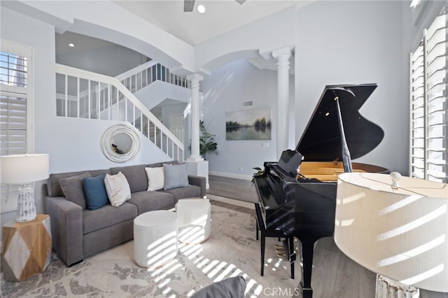 living area with stairs, recessed lighting, wood finished floors, arched walkways, and ornate columns