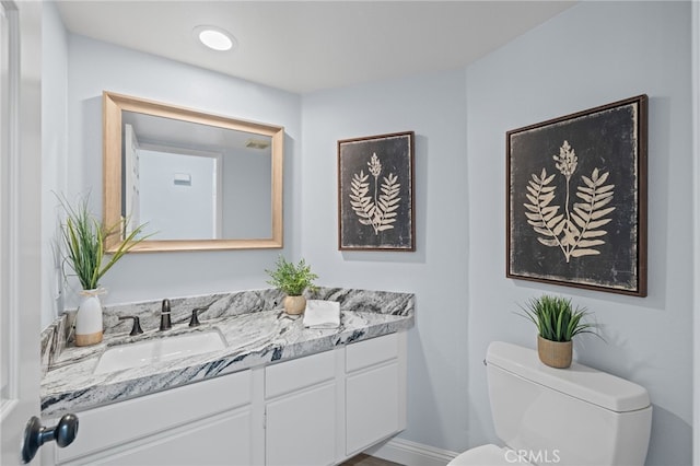 bathroom featuring vanity, toilet, and baseboards