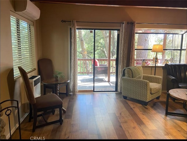 living area featuring an AC wall unit, wood finished floors, and baseboards