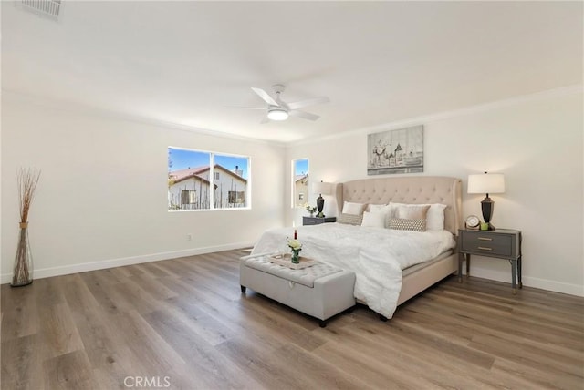 bedroom with visible vents, ornamental molding, ceiling fan, wood finished floors, and baseboards