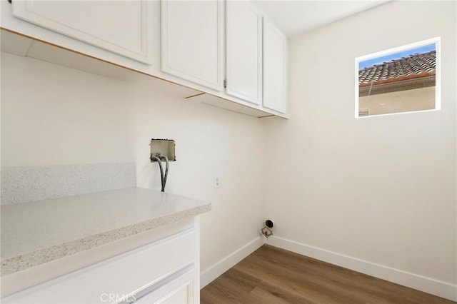 clothes washing area featuring hookup for a washing machine, cabinet space, dark wood finished floors, and baseboards