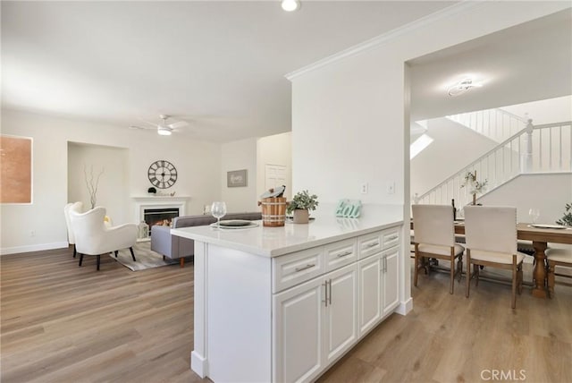 kitchen featuring a lit fireplace, light wood-style flooring, light countertops, and open floor plan