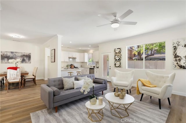 living room featuring light wood-type flooring, ceiling fan, baseboards, and recessed lighting