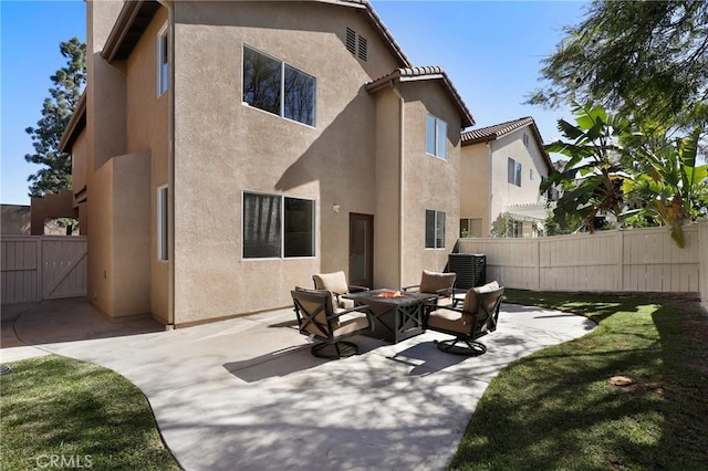 rear view of house featuring a patio, fence, a fire pit, and stucco siding