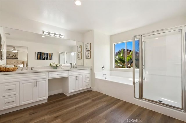 full bathroom with double vanity, a shower stall, a sink, and wood finished floors