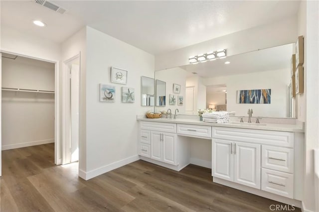 full bathroom featuring double vanity, wood finished floors, a sink, and visible vents