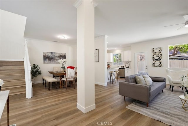 living room featuring a wealth of natural light, stairway, light wood-style flooring, and baseboards