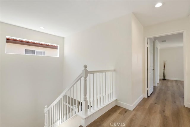 hall with recessed lighting, visible vents, an upstairs landing, wood finished floors, and baseboards