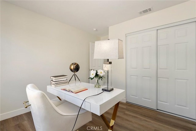 office area with dark wood-style flooring, visible vents, and baseboards