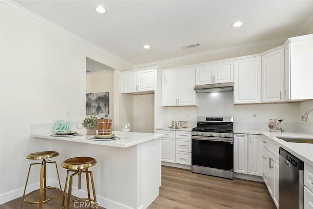 kitchen featuring under cabinet range hood, a sink, visible vents, white cabinets, and appliances with stainless steel finishes