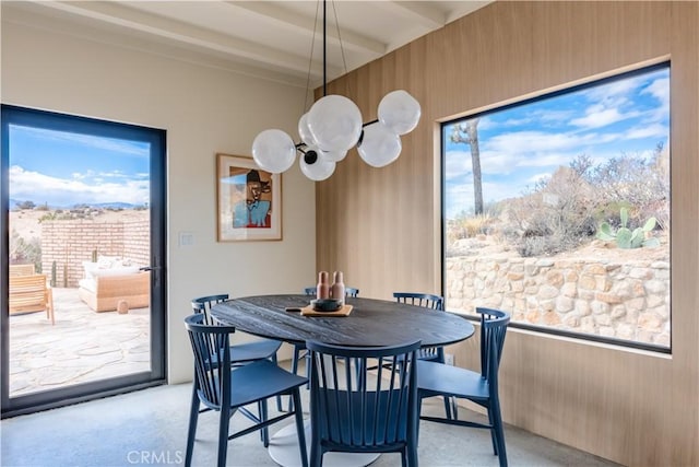 dining area featuring wood walls and beamed ceiling