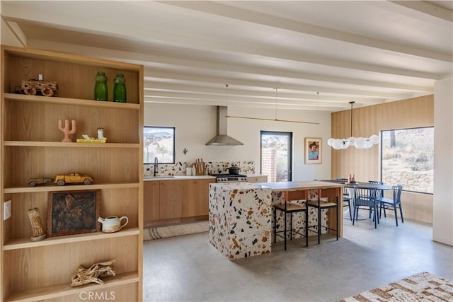 kitchen with finished concrete flooring, wall chimney exhaust hood, modern cabinets, light countertops, and a sink