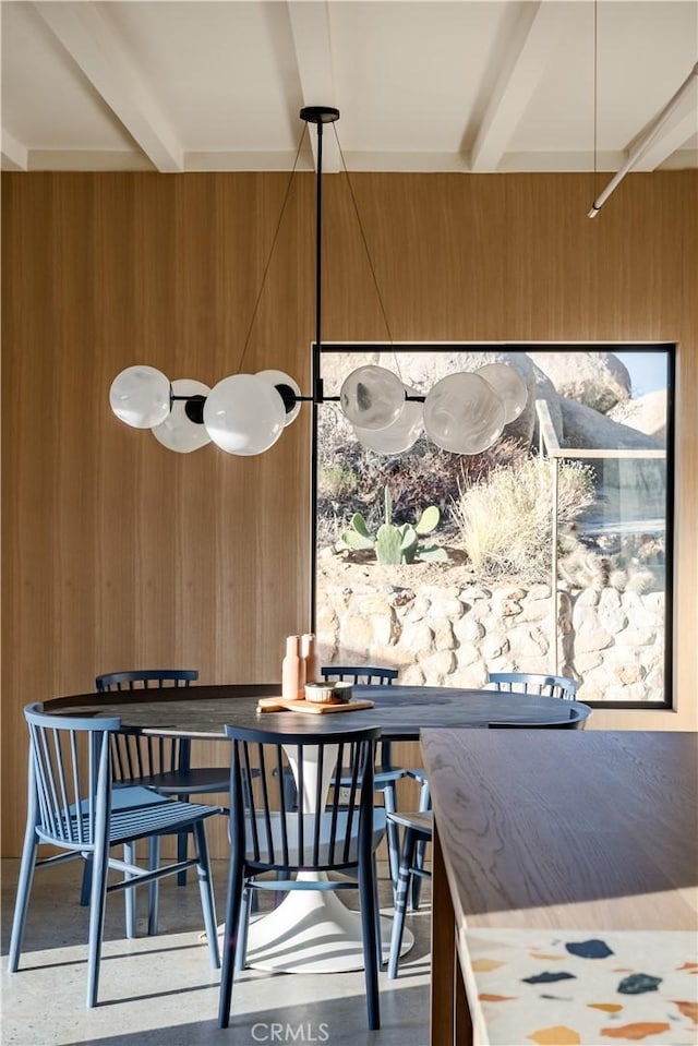 dining room with beam ceiling and wooden walls