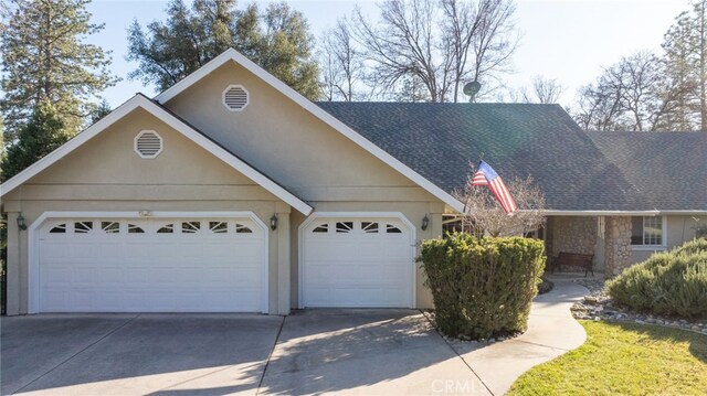 view of front of home featuring an attached garage, a shingled roof, concrete driveway, stone siding, and stucco siding