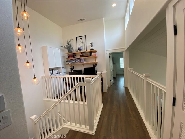 hall featuring an upstairs landing, visible vents, a towering ceiling, and wood finished floors