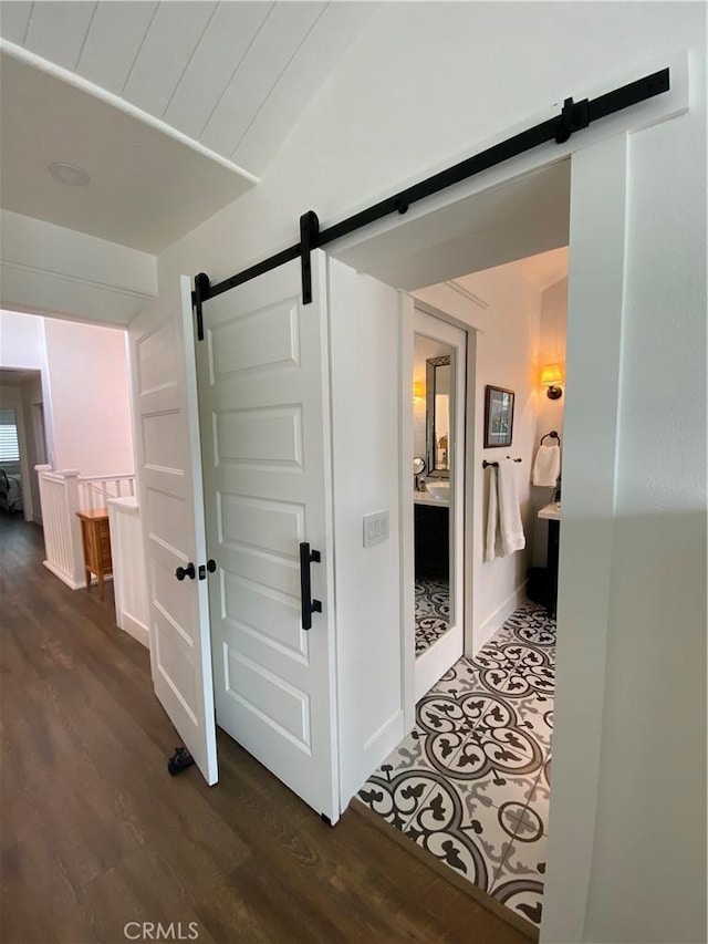 corridor with a barn door and dark wood-style floors