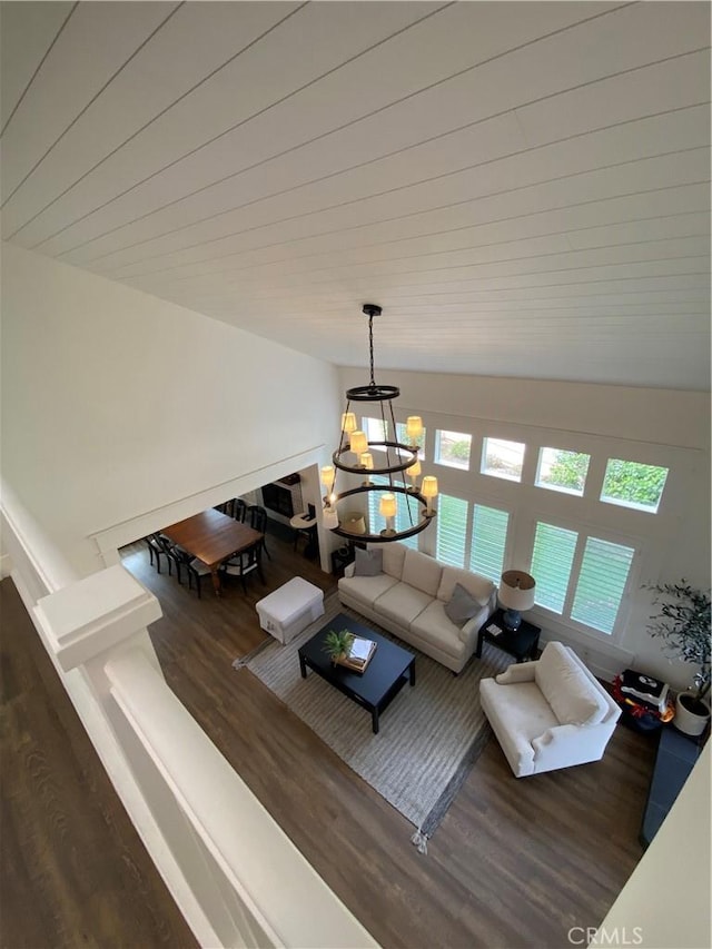 living room featuring a notable chandelier, wood finished floors, and vaulted ceiling