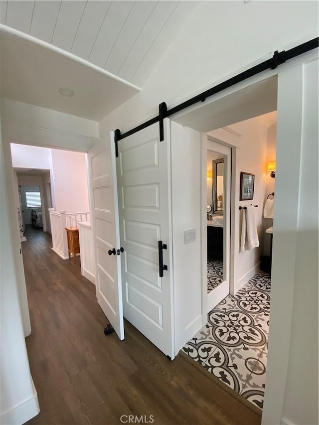 corridor featuring a barn door and dark wood-style flooring