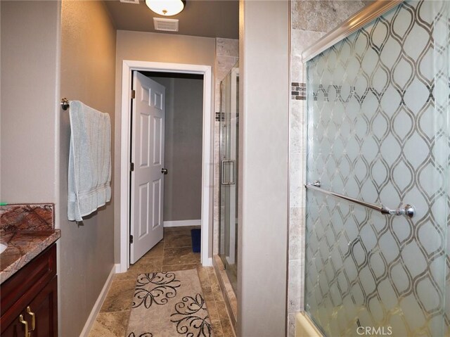 bathroom featuring visible vents, tiled shower, vanity, and baseboards