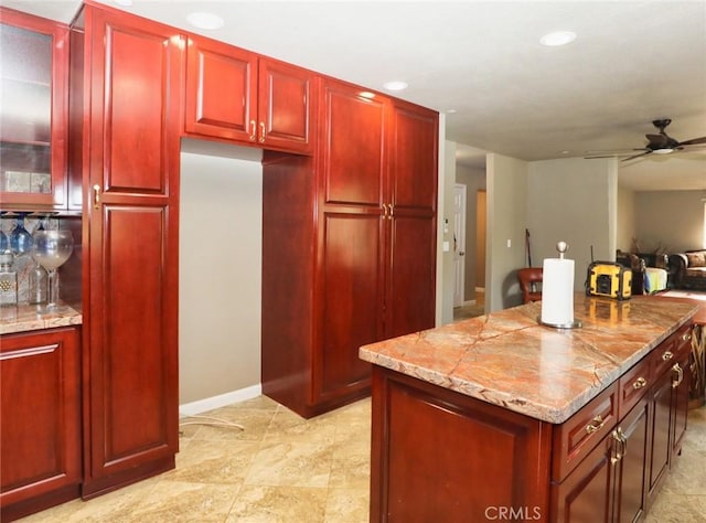 kitchen featuring a center island, glass insert cabinets, ceiling fan, and reddish brown cabinets