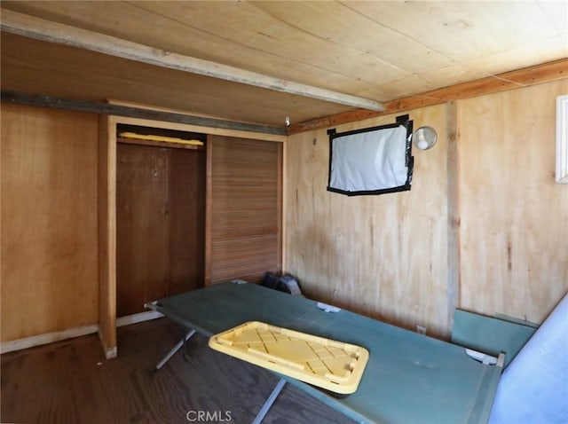 bedroom with a closet, wood walls, and wood finished floors