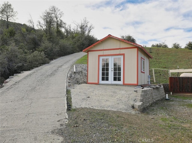 view of outbuilding featuring french doors, an outdoor structure, and fence