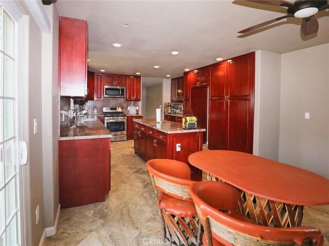 kitchen with recessed lighting, stainless steel appliances, decorative backsplash, dark brown cabinets, and a center island