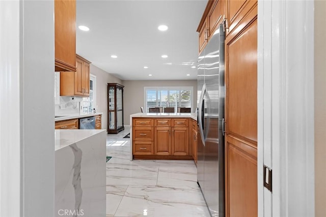 kitchen featuring marble finish floor, stainless steel appliances, brown cabinetry, and a peninsula