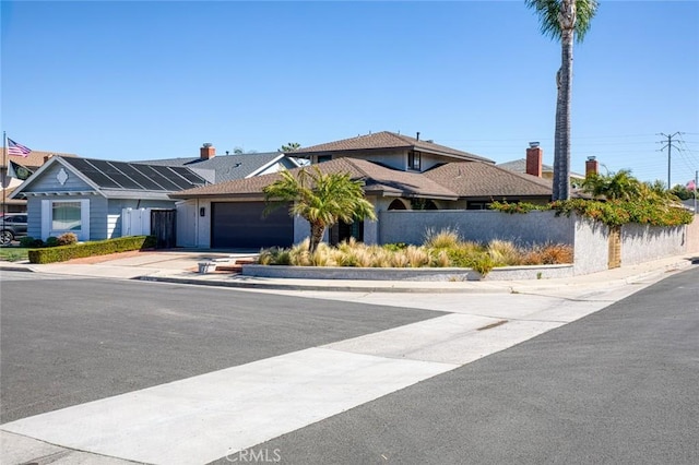 view of front of home featuring driveway, an attached garage, and fence