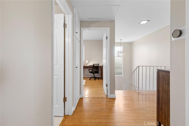 hall featuring light wood finished floors, baseboards, and an upstairs landing