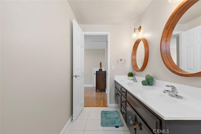 bathroom featuring double vanity, tile patterned flooring, a sink, and baseboards