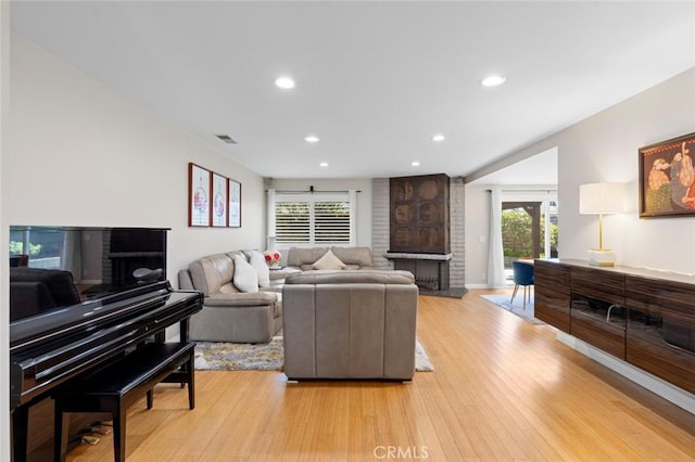 living room with light wood-type flooring, a brick fireplace, visible vents, and recessed lighting