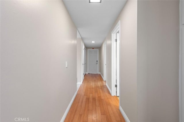 hall with light wood-type flooring and baseboards