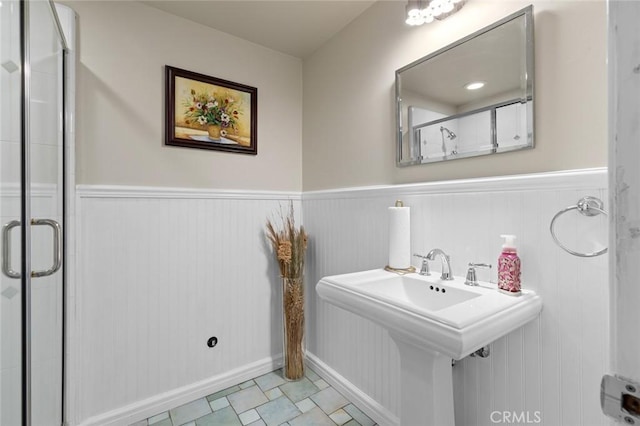 full bath with a sink, wainscoting, and a shower stall