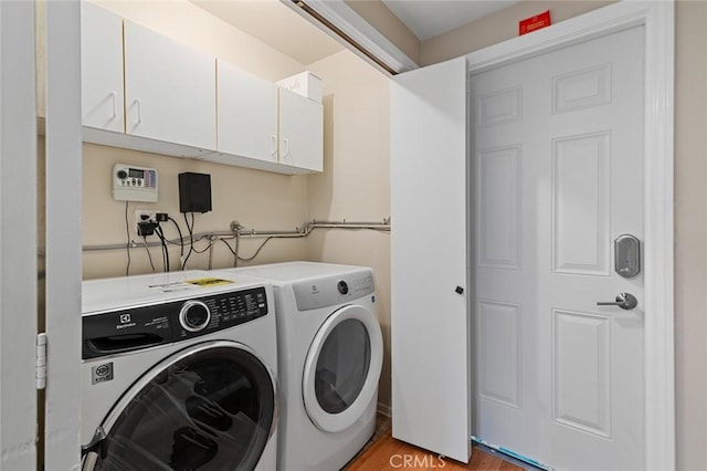 laundry area with cabinet space, washing machine and dryer, and light wood-style floors