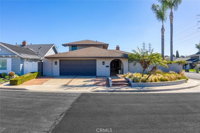 view of front of property featuring concrete driveway, fence, an attached garage, and stucco siding