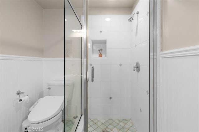 full bath featuring a wainscoted wall, a shower stall, and toilet